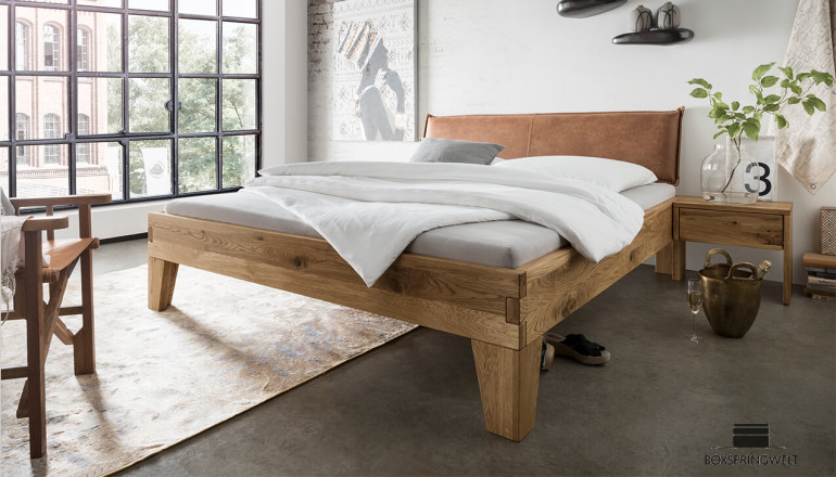 Lit en bois massif Nils 160x220 en chêne sauvage ; tête de lit revêtue de cuir marron avec passepoil décoratif